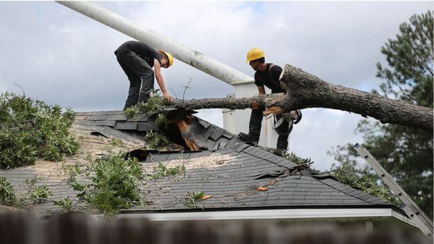 Two men are working on a roof that is being cut down.